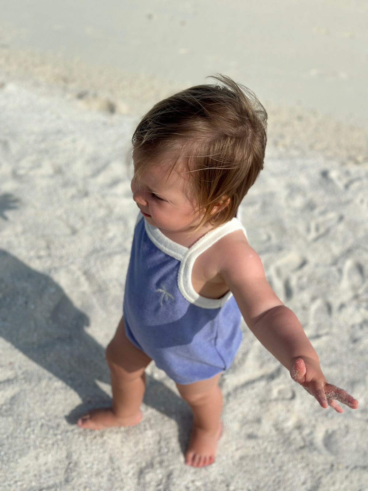 Happymess Terry Romper in Berry Breeze, on a child at the beach.